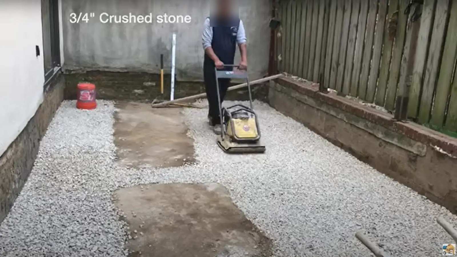 Crew compacting the crushed stone base for a new concrete backyard
