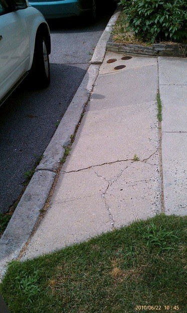 Before: cracked curb and sidewalk at a driveway apron