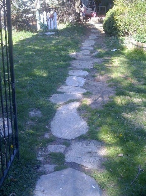 Before: worn stepping-stone path ahead of a new concrete walkway
